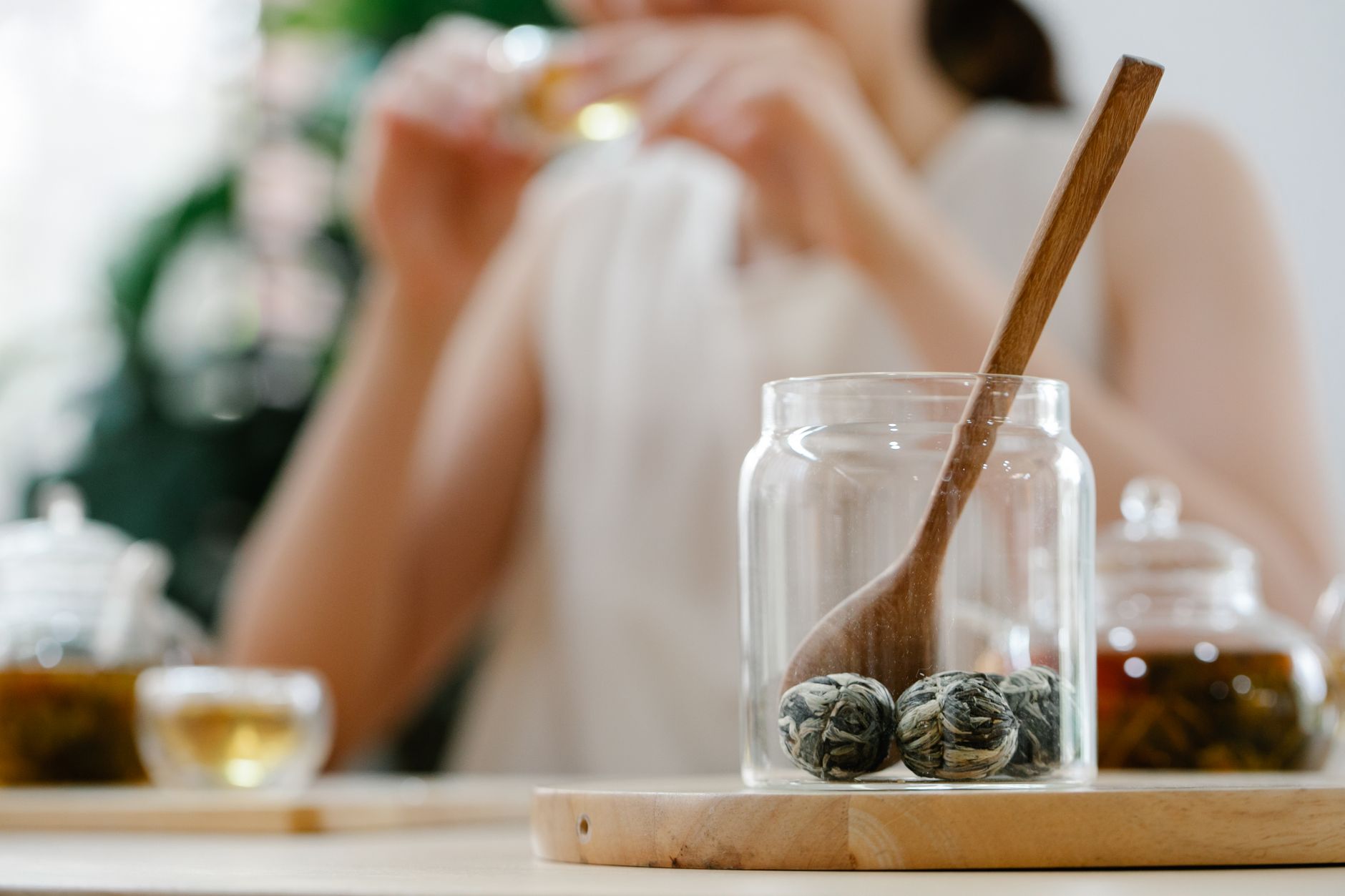 various types of loose leaf teas and herbal infusions in small jars, next to a tea infuser and a notebook. Warm, inviting atmosphere.